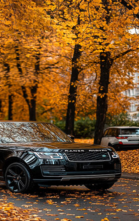 a close up of a black suv parked on a street with trees in the background
